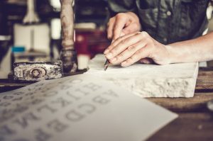 A person chiselling letters into stone