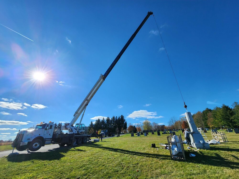 Crane installing granite statue of christ