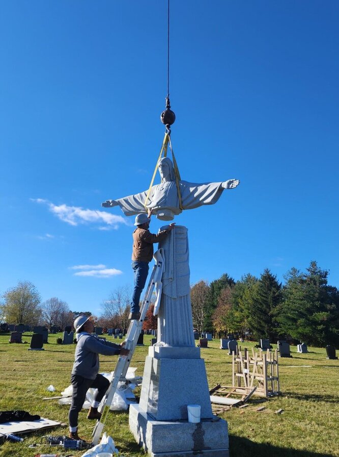 Installing granite holy redeemer statue in cemetary